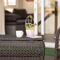 Nyugodt reggelek és pihenés a vendégház fedett teraszán. Kényelmes teraszrészlet kávéval és tóparti apartmannal a Barbi-tó Vendégháznál
